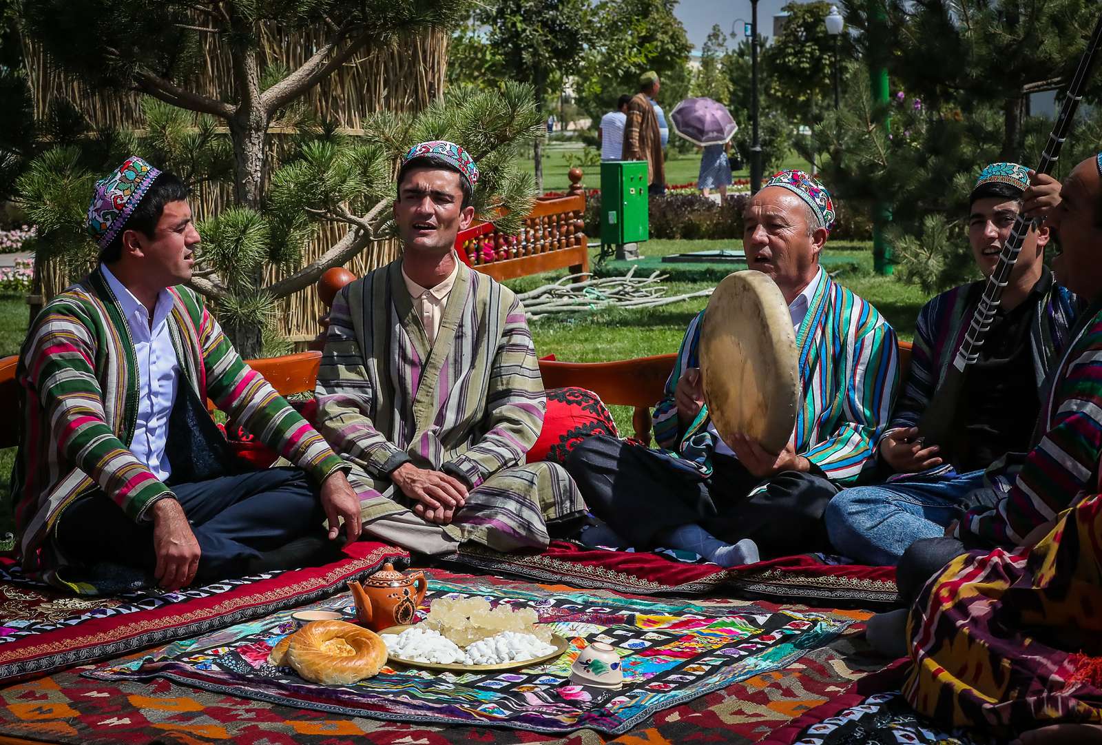 A dastarkhan laid with bread and tea, and musicians playing nearby