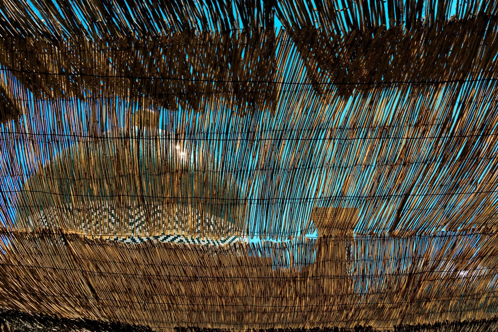 Sunlight through a reed awning over a tiled dome, Khiva