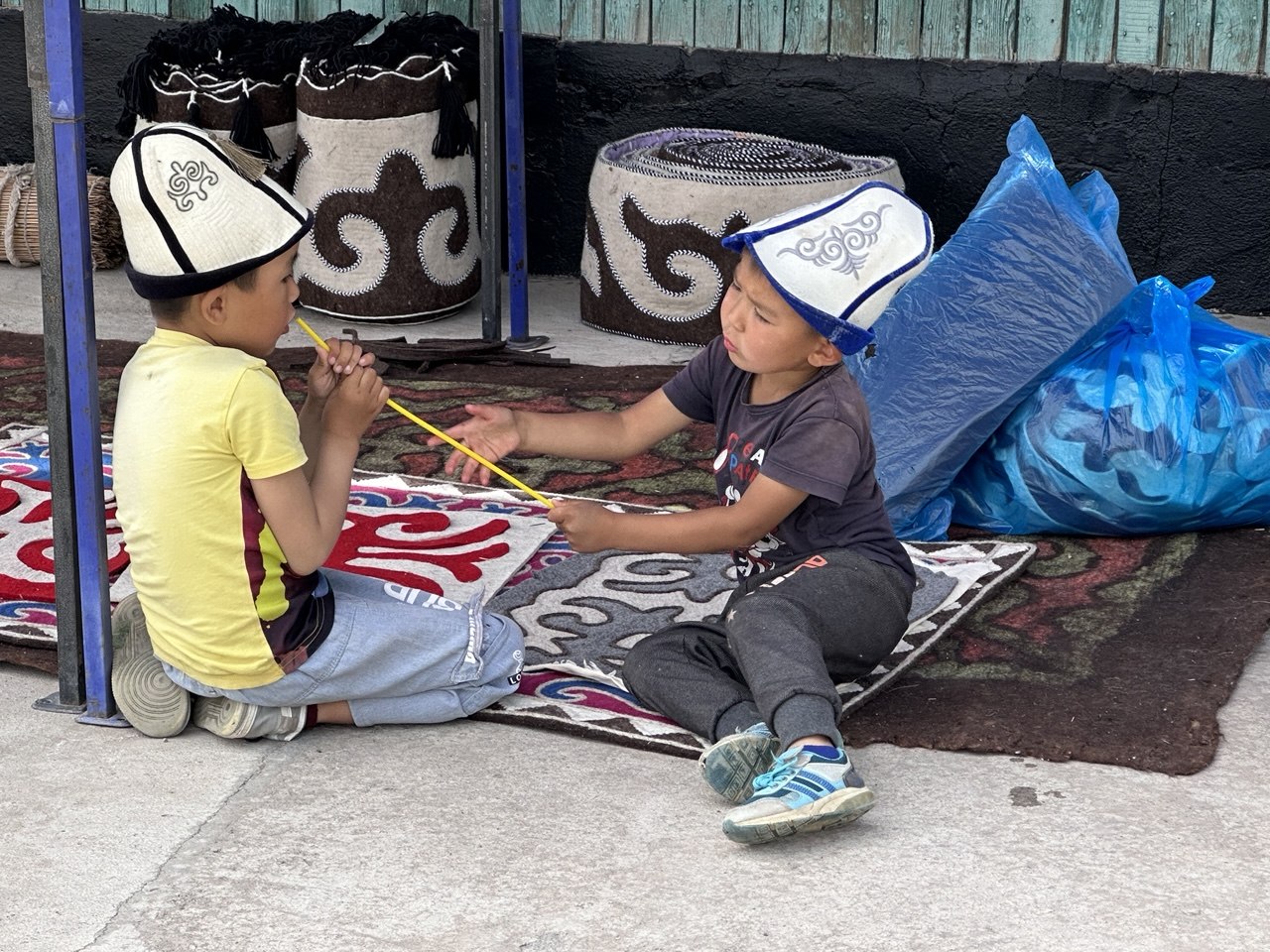 Boys in kalpak felt hats on shyrdak carpets