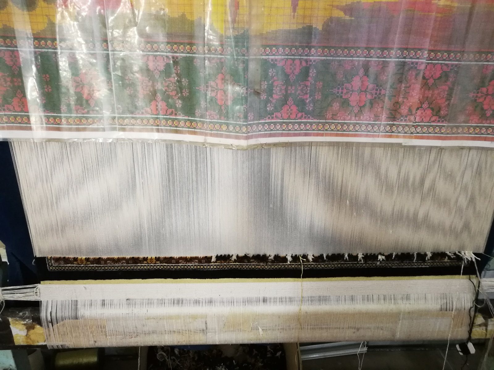 A silk carpet on the loom under its pattern chart