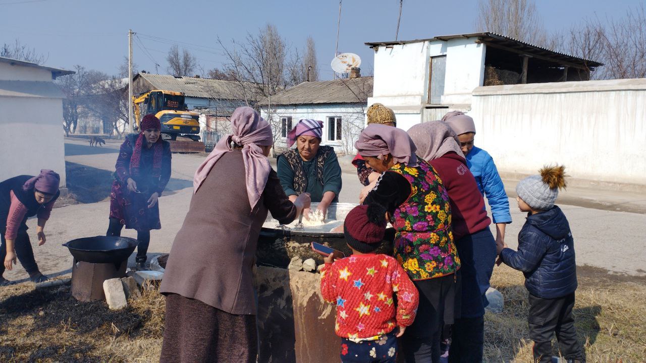 Neighbours taking turns at the sumalak kazan in a village yard